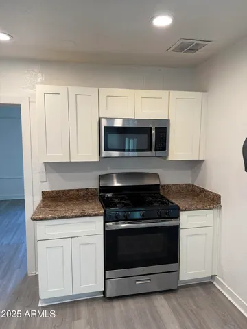 a kitchen with granite countertop white cabinets and stainless steel appliances