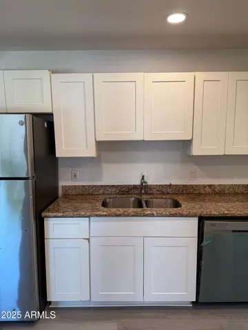 a kitchen with granite countertop white cabinets and a stainless steel appliances