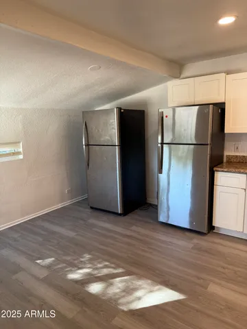 a view of a refrigerator in kitchen and an empty room