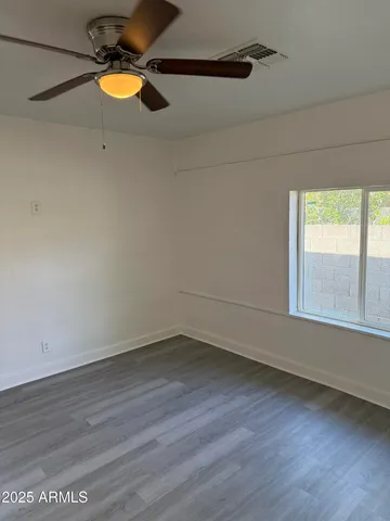 a view of an empty room with wooden floor and window
