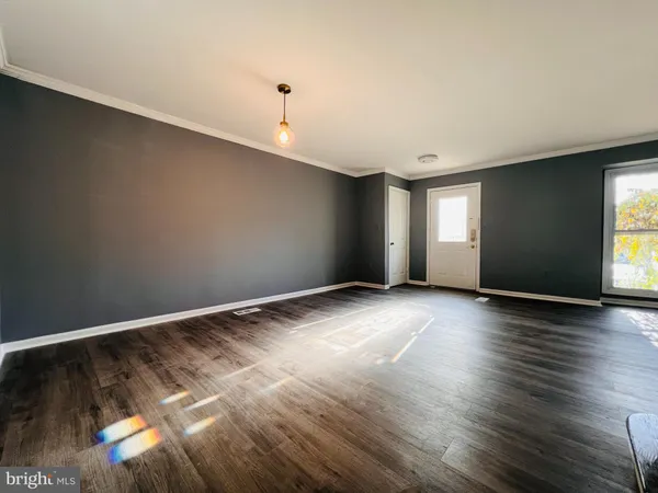a view of an empty room with window and wooden floor