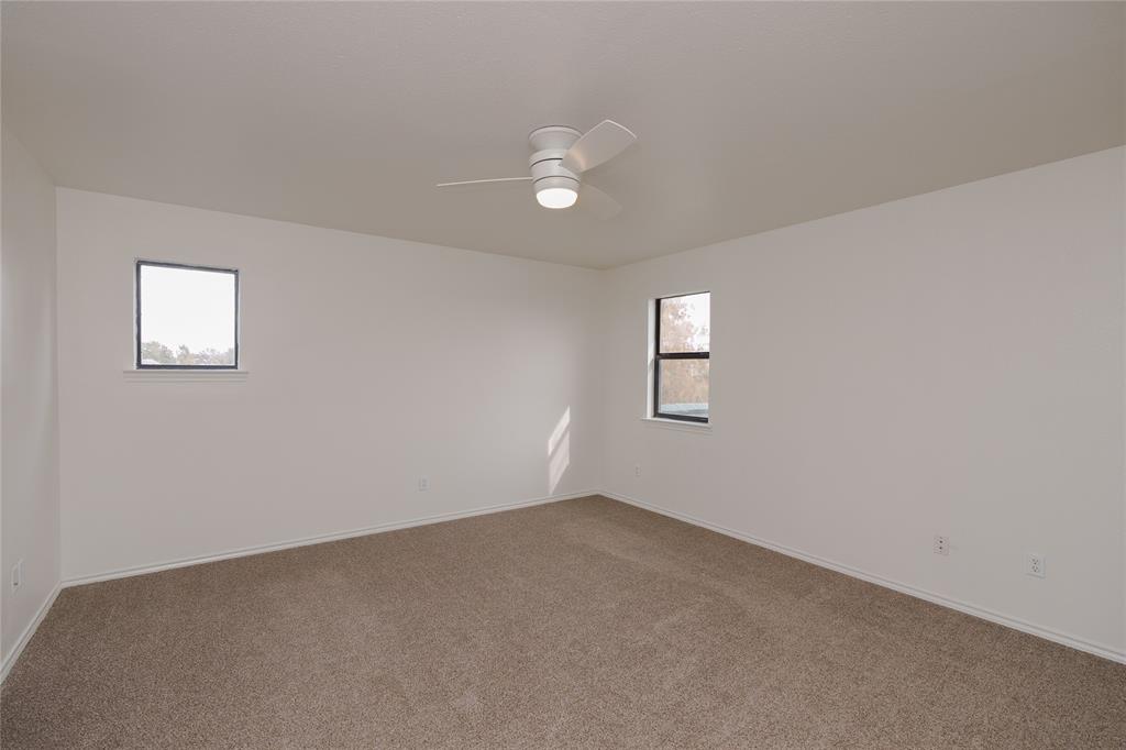 364 Parker Road, Unit A Van Alstyne, TX 75495 - Photo 34 of 39 Spacious room with plush carpet flooring, neutral paint palette, two windows, and a ceiling fan with integrated lighting