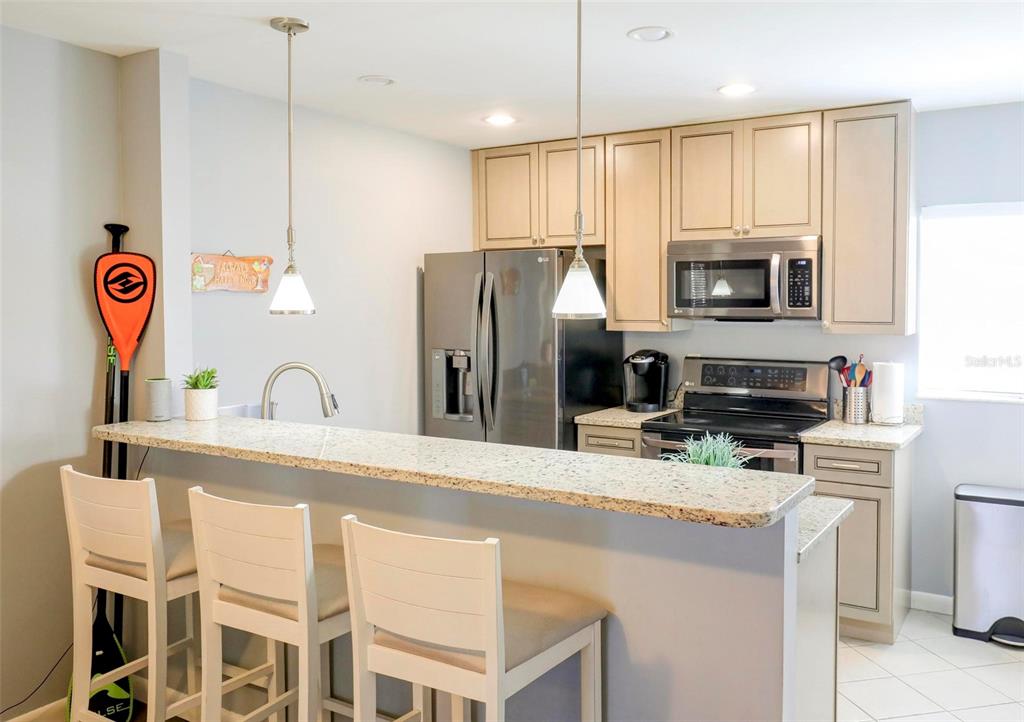 8911 Blind Pass Road, Unit 321 St. Pete Beach, FL 33706 - Photo 14 of 55 a kitchen with stainless steel appliances granite countertop a refrigerator a stove a sink a microwave and island with wooden floor