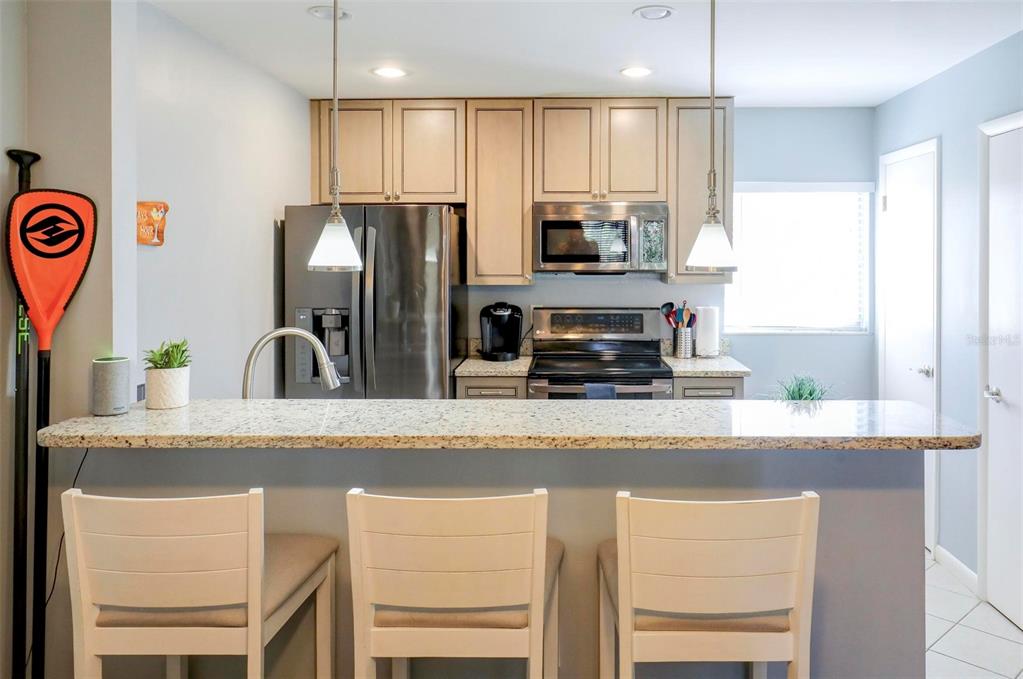 8911 Blind Pass Road, Unit 321 St. Pete Beach, FL 33706 - Photo 15 of 55 a kitchen with stainless steel appliances granite countertop white cabinets a refrigerator a sink a stove and a refrigerator