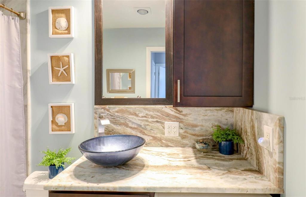 8911 Blind Pass Road, Unit 321 St. Pete Beach, FL 33706 - Photo 17 of 55 a bathroom with a granite countertop sink and a mirror
