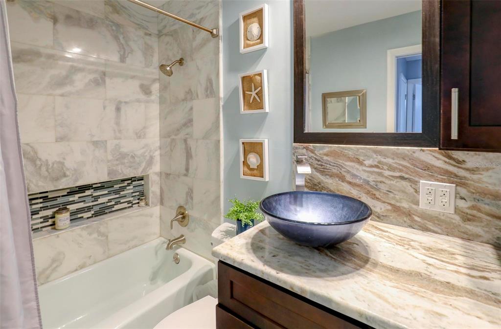 8911 Blind Pass Road, Unit 321 St. Pete Beach, FL 33706 - Photo 19 of 55 a bathroom with a granite countertop toilet sink and mirror
