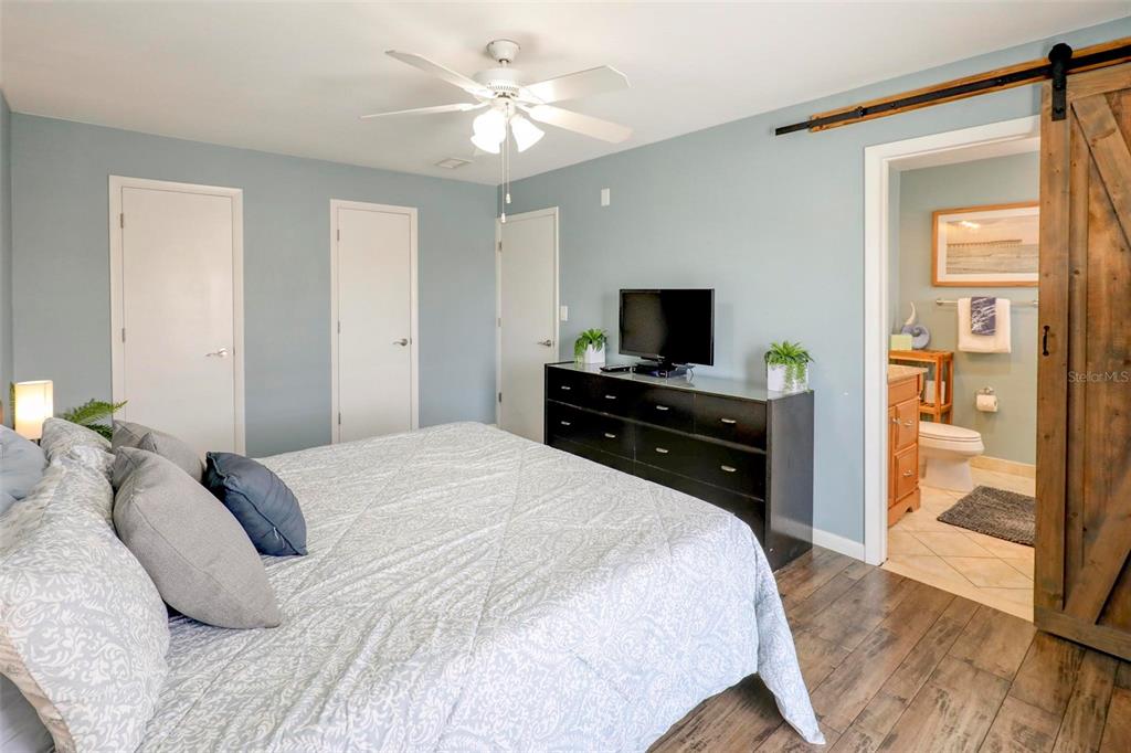 8911 Blind Pass Road, Unit 321 St. Pete Beach, FL 33706 - Photo 30 of 55 a bedroom with a bed and a flat tv screen on dresser