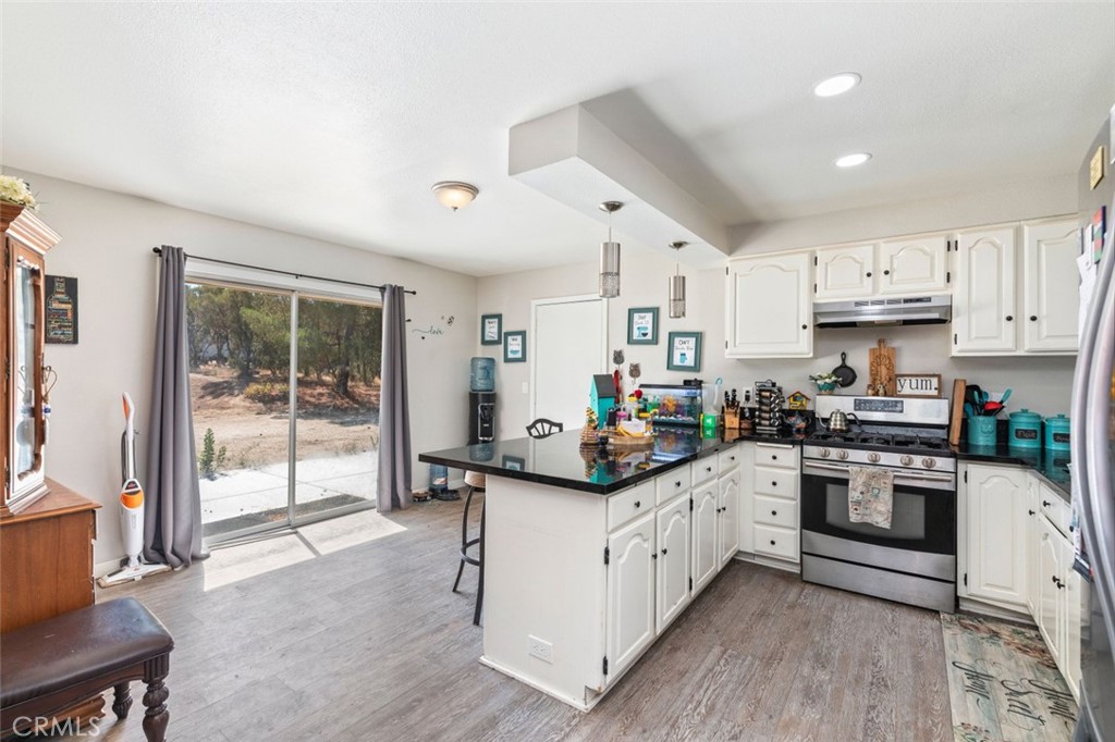 38855 Howard Road Anza, CA 92539 - Photo 5 of 54 a kitchen with stainless steel appliances granite countertop a stove top oven a sink dishwasher a dining table and chairs with wooden floor