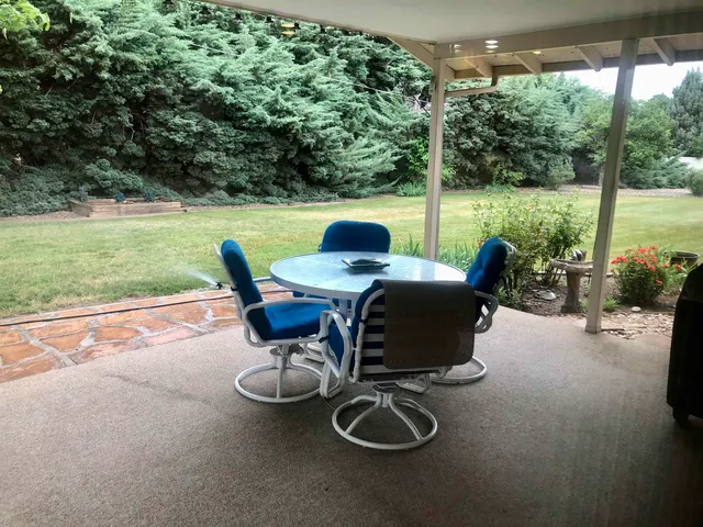 a view of a patio with chairs and table in the yard