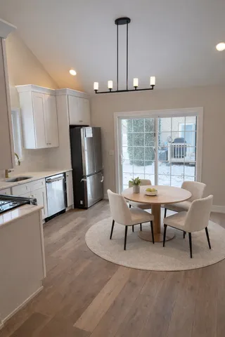 a open kitchen with stainless steel appliances granite countertop a stove a refrigerator a kitchen island a dining table and chairs