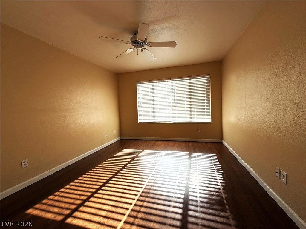 4955 South Lindell Road, Unit 203 Las Vegas, NV 89118 - Photo 10 of 31 Natural light filters into this bedroom, highlighting the rich hardwood flooring and offering a serene atmosphere.