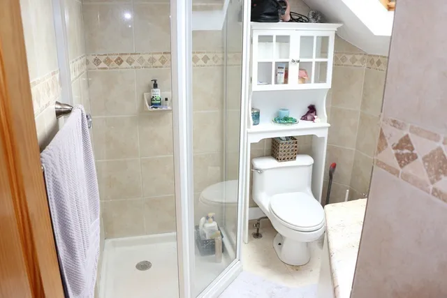 a white toilet sitting next to a bathroom sink and a shower