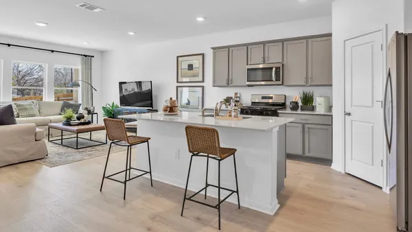 a kitchen with stainless steel appliances granite countertop a stove top oven a sink a refrigerator and white cabinets with wooden floor