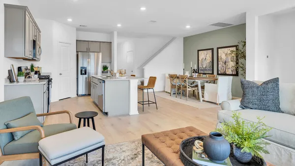a living room with furniture potted plant and kitchen view