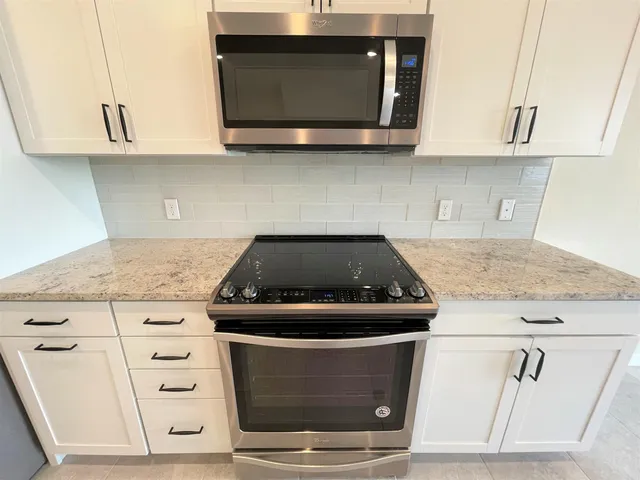 a kitchen with granite countertop white cabinets and a sink