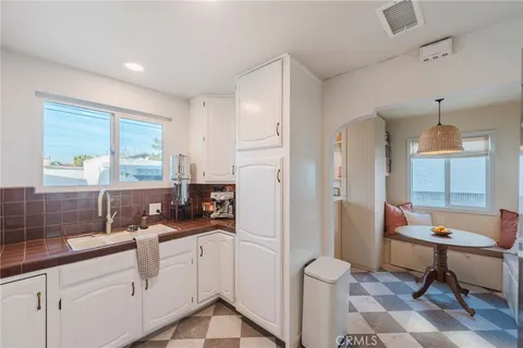 a kitchen with a sink dishwasher a dining table and chairs with wooden floor