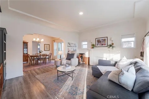 a living room with furniture and a dining table with wooden floor