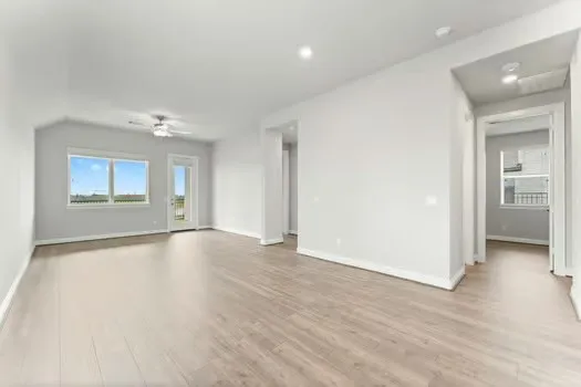 an empty room with wooden floor cabinet and windows