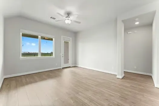 a view of an empty room with wooden floor and a window