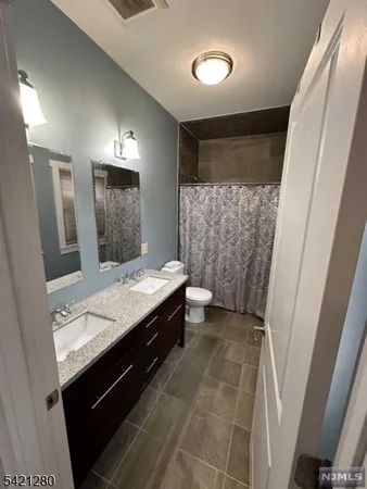 a bathroom with a double vanity sink toilet and mirror