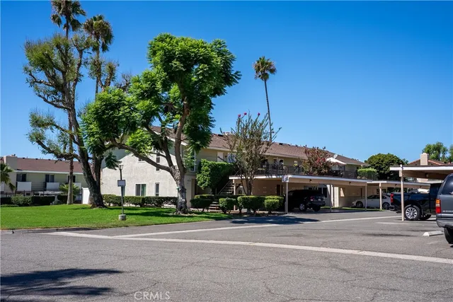 a front view of a building with a garden and tree