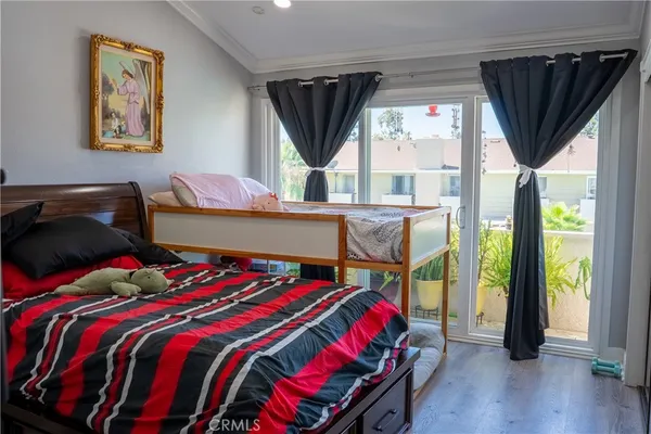 a bedroom with a bed a dresser and a large window