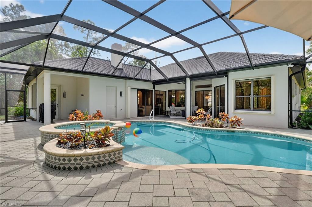Integrated pool / spa with a sunroom, a lanai, and a patio