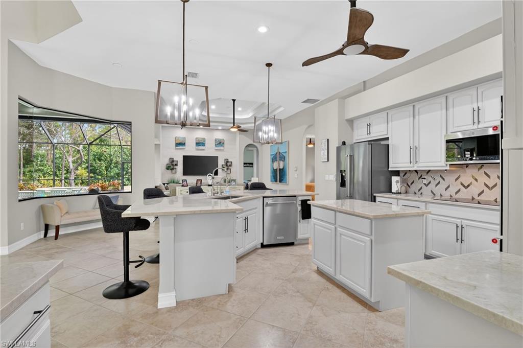 2360 19th Street Southwest Naples, FL 34117 - Photo 42 of 43 a kitchen with white cabinets and chandelier