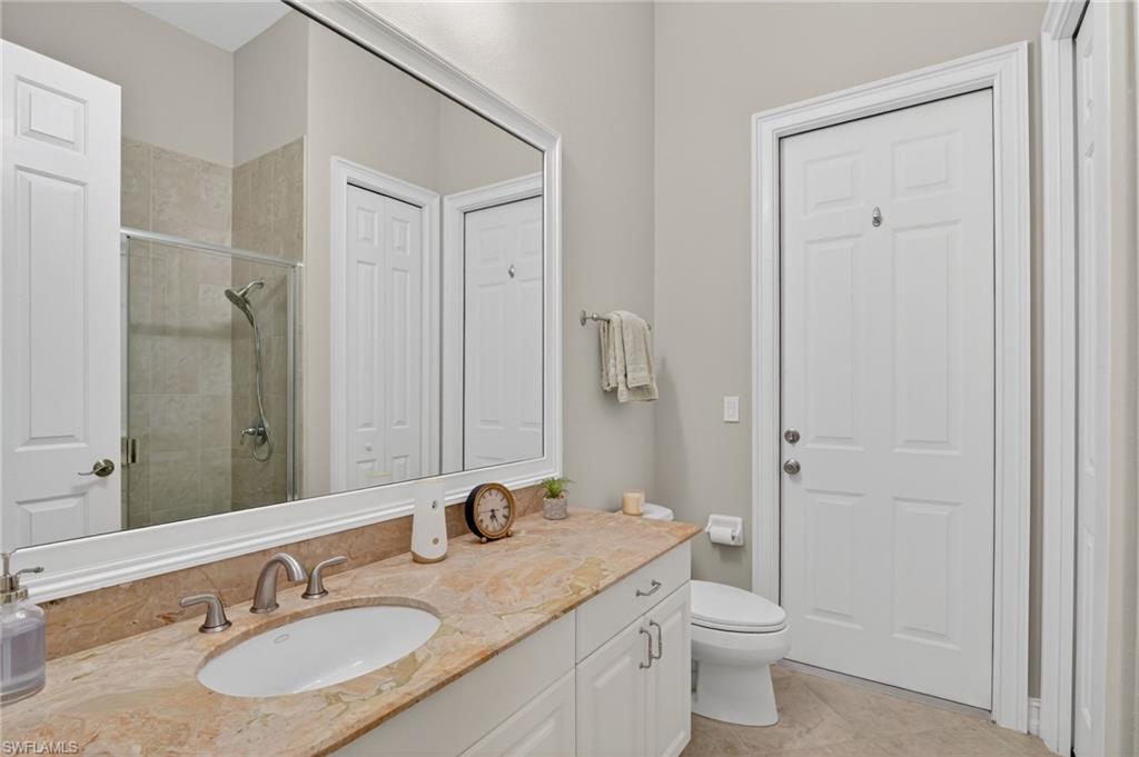 2360 19th Street Southwest Naples, FL 34117 - Photo 34 of 43 a bathroom with a granite countertop sink toilet a mirror a vanity and shower