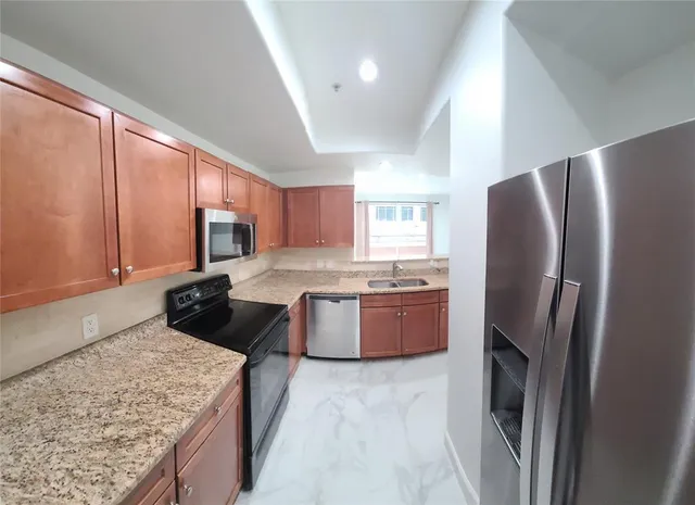 a view of kitchen with stainless steel appliances granite countertop a stove top oven a sink and a refrigerator