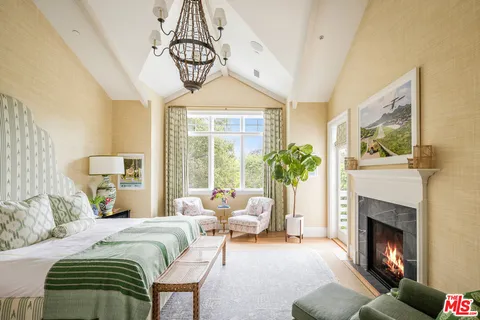 a bedroom with a bed a chandelier and a fireplace