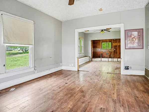an empty room with wooden floor and windows