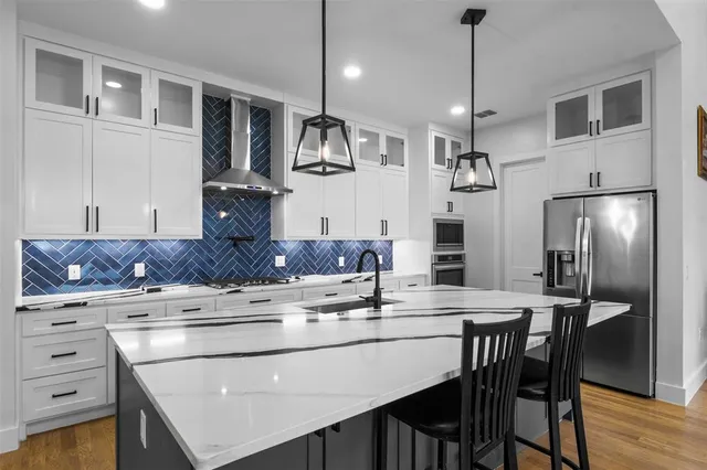 a kitchen with stainless steel appliances kitchen island granite countertop a table chairs stove and refrigerator