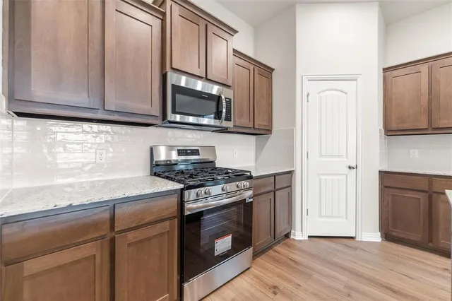 a kitchen with stainless steel appliances granite countertop a stove microwave and sink