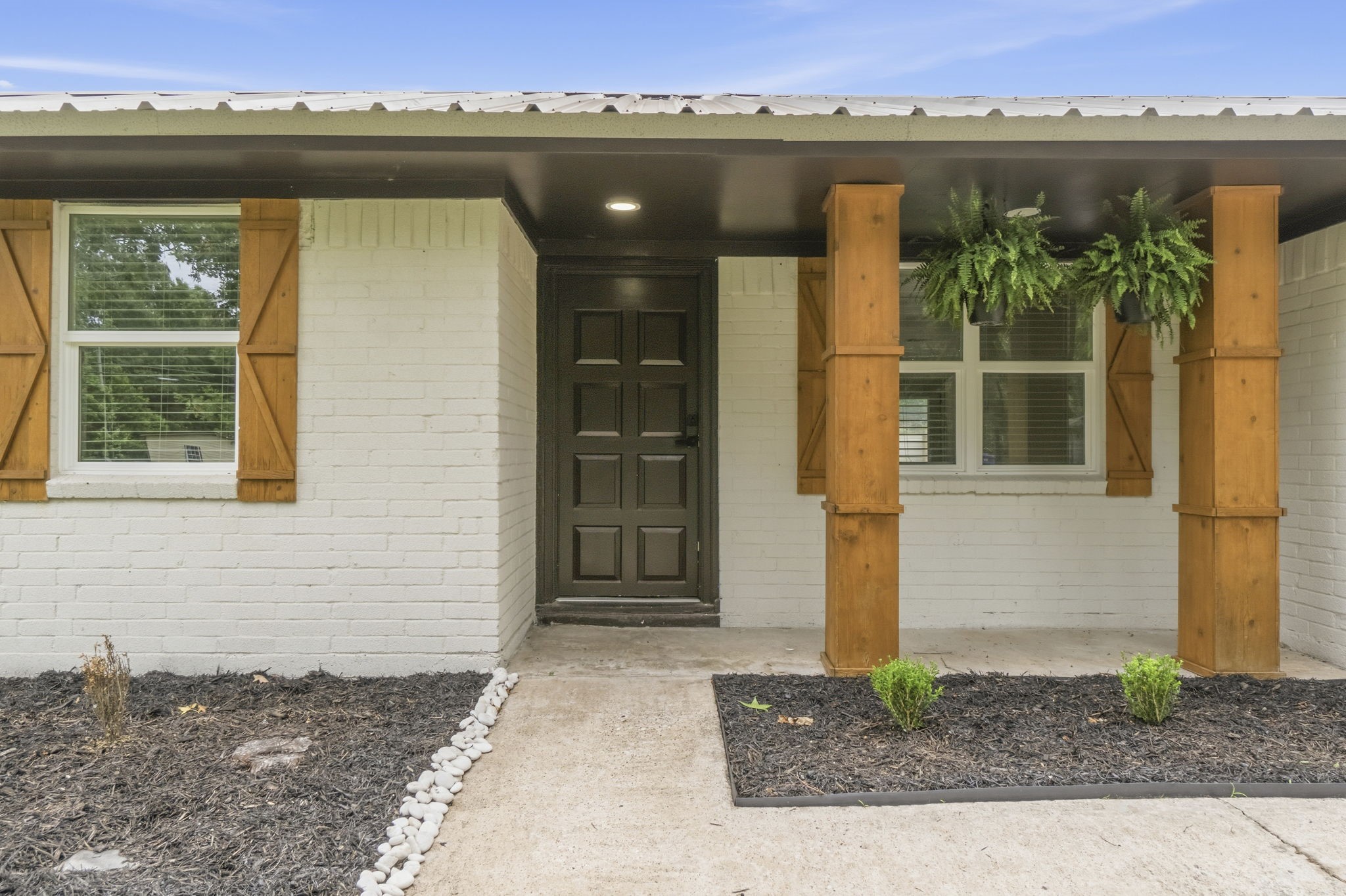 14850 Coaltown Road Willis, TX 77378 - Photo 3 of 41 Inviting covered front porch with rustic cedar accents, modern black front door, recessed lighting, and fresh landscaping creating a warm welcome.