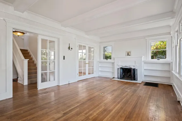 a view of a livingroom with wooden floor a fireplace and windows