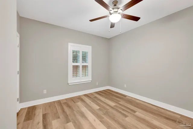an empty room with a chandelier fan and windows