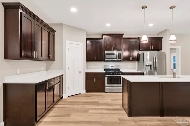 a kitchen with stainless steel appliances granite countertop a stove a sink dishwasher a refrigerator and a oven with wooden floor