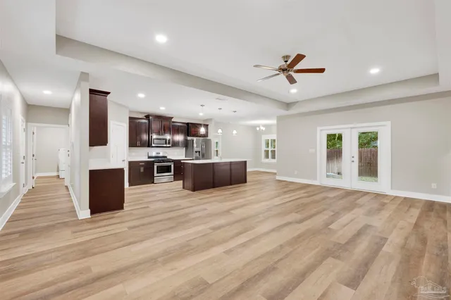 a large kitchen with kitchen island a stove a refrigerator a sink dishwasher with a dining table and chairs with wooden floor