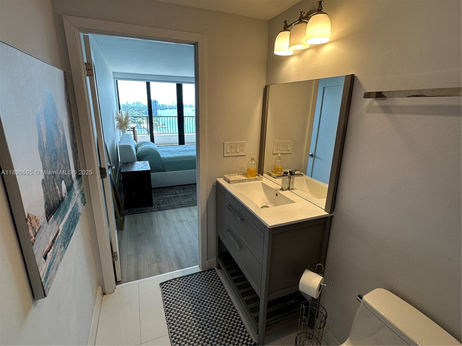 555 Northeast 15th Street, Unit 23B Miami, FL 33132 - Photo 17 of 32 a bathroom with a sink vanity granite toilet and a mirror