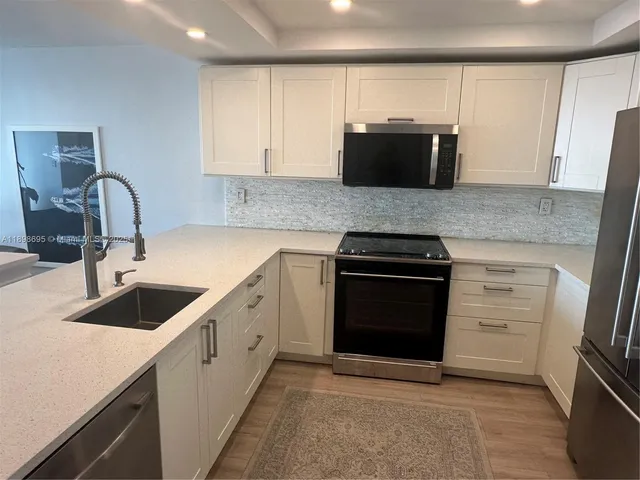 a kitchen with granite countertop white cabinets and stainless steel appliances