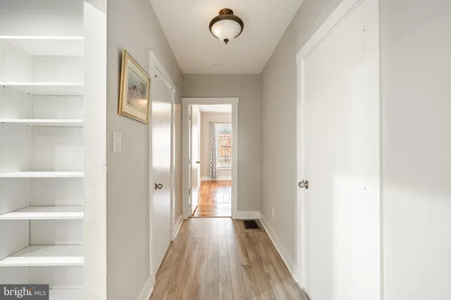 a view of a hallway with wooden floor and a bathroom