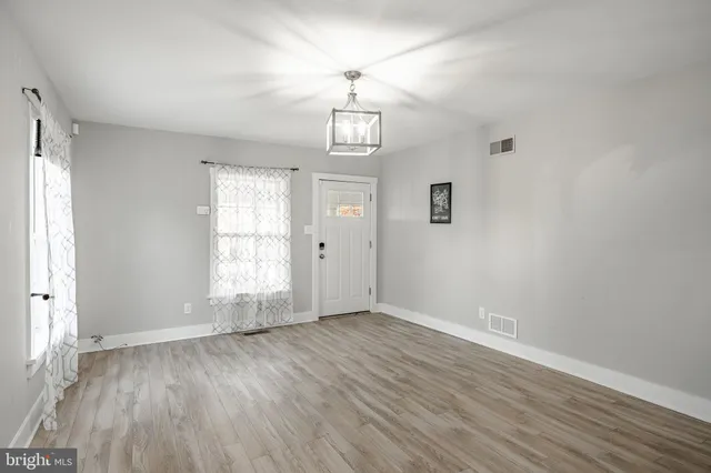 an empty room with wooden floor window and windows