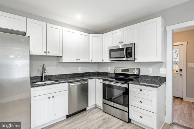 a kitchen with granite countertop white cabinets white stainless steel appliances and a sink