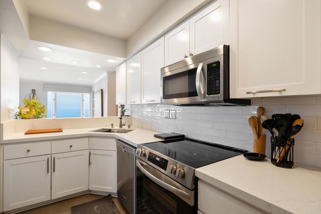 940 Sealane Drive, Unit 14 Encinitas, CA 92024 - Photo 10 of 45 a kitchen with stainless steel appliances a stove a sink a microwave cabinets and a counter top space