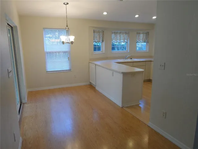 a view of an empty room with kitchen and window