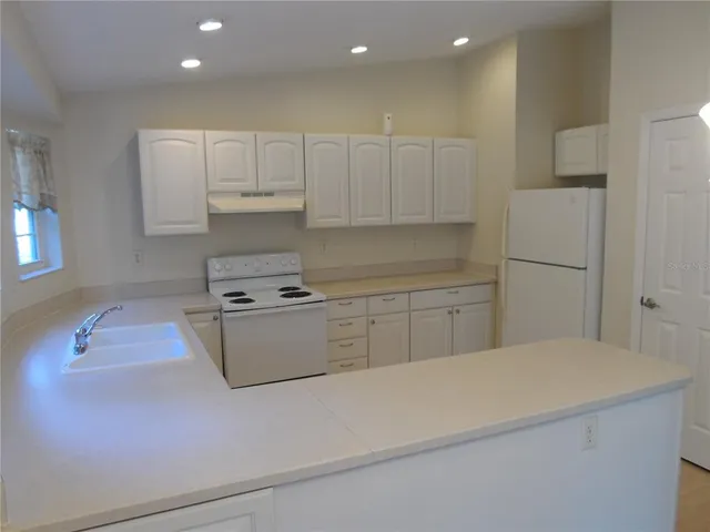 a kitchen with white cabinets and white appliances
