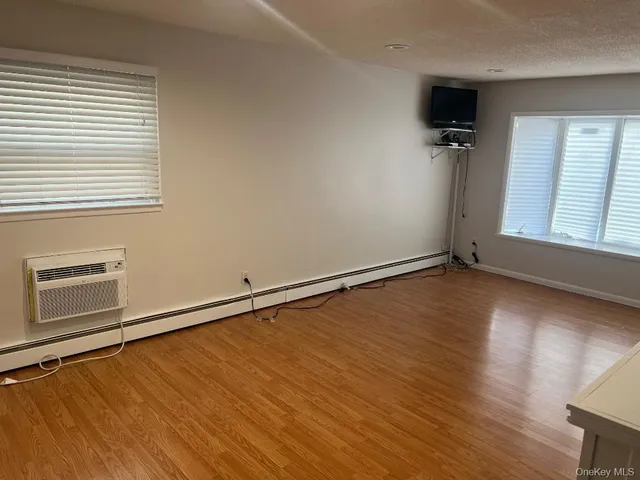 an empty room with wooden floor cabinet and windows