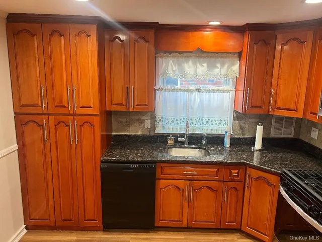 a kitchen with granite countertop wooden cabinets a sink and a window