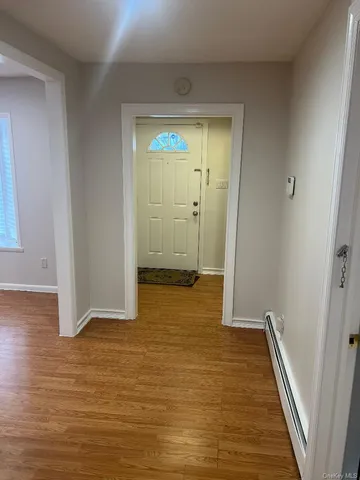 a view of an empty room with wooden floor and a bathroom